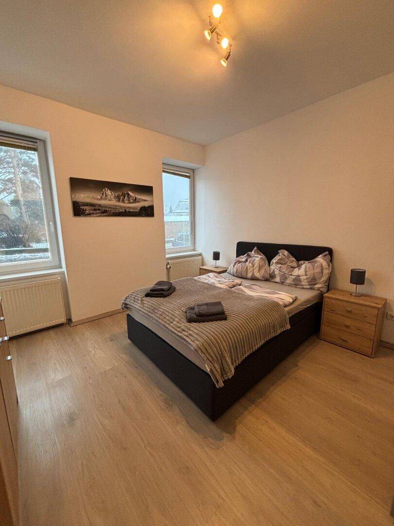 Helles Schlafzimmer mit Doppelbett, Nachttischen und Laminatboden.