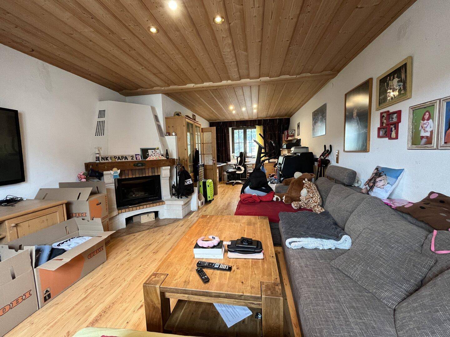 Geräumiges Wohnzimmer mit Kamin, Holzbalkendecke und Laminatboden.