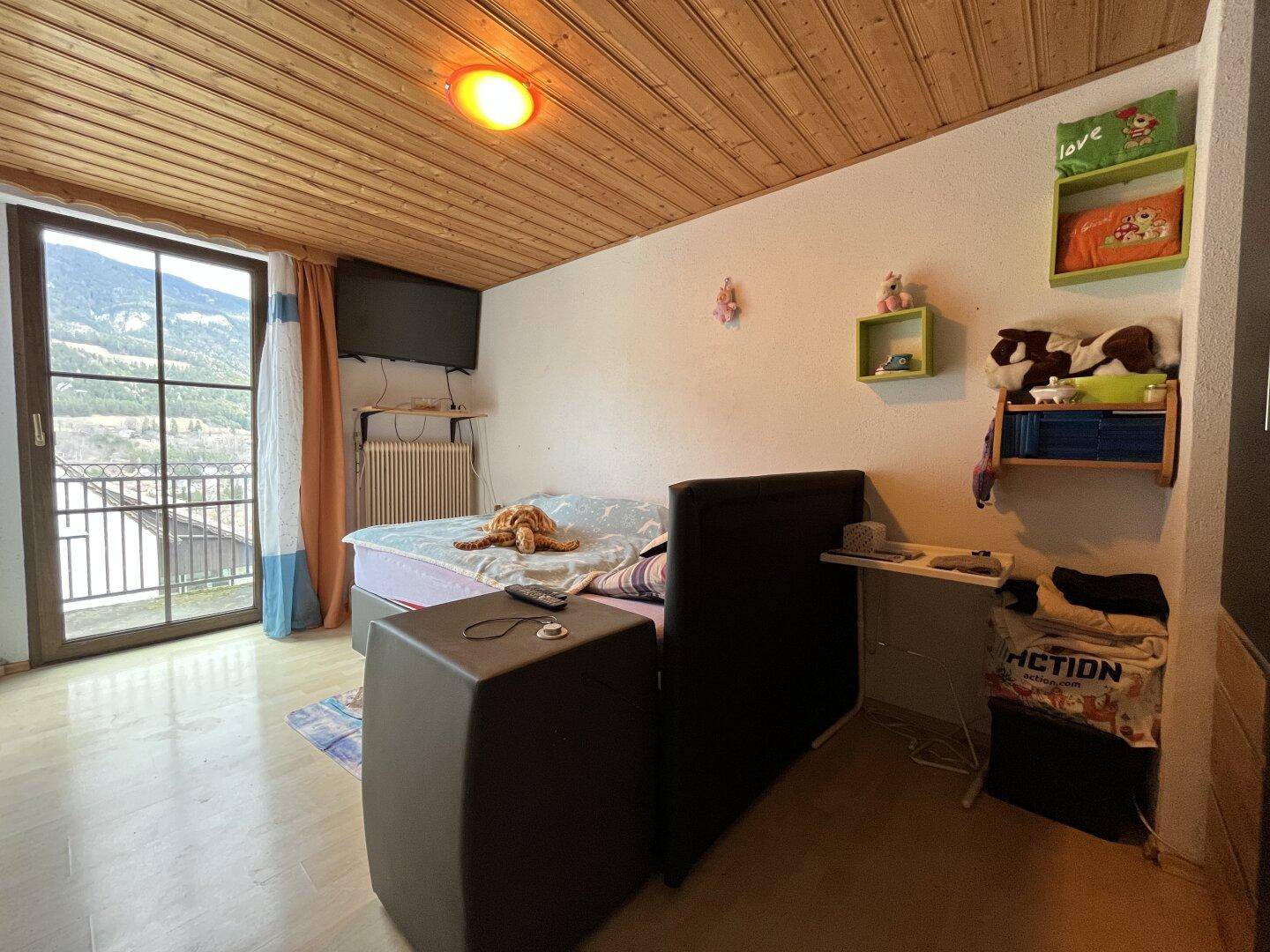 Schlafzimmer mit Bergblick, Laminatboden und Zugang zu einem Balkon.