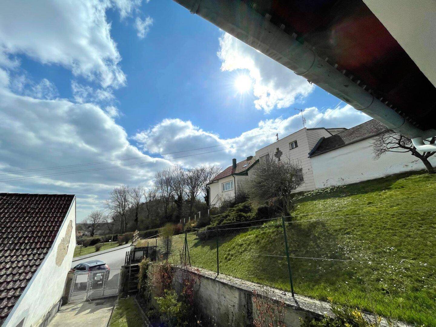 Blick auf die grüne Umgebung und Nachbarhäuser unter blauem Himmel.
