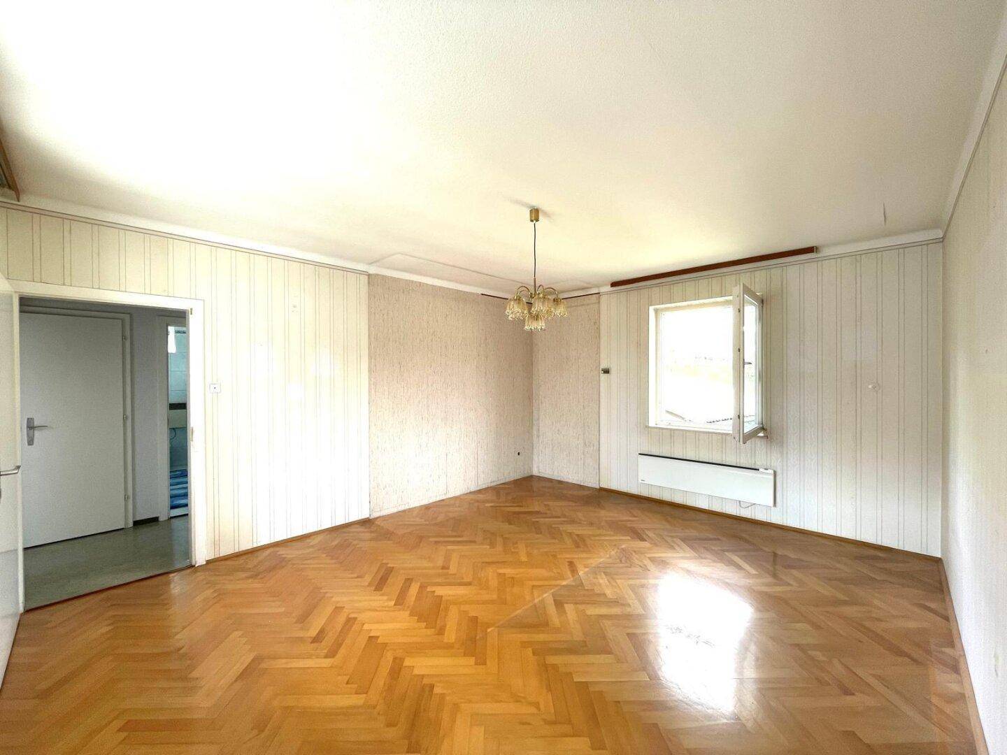 Helles Zimmer mit Parkettboden und Tapeten im Landhausstil.