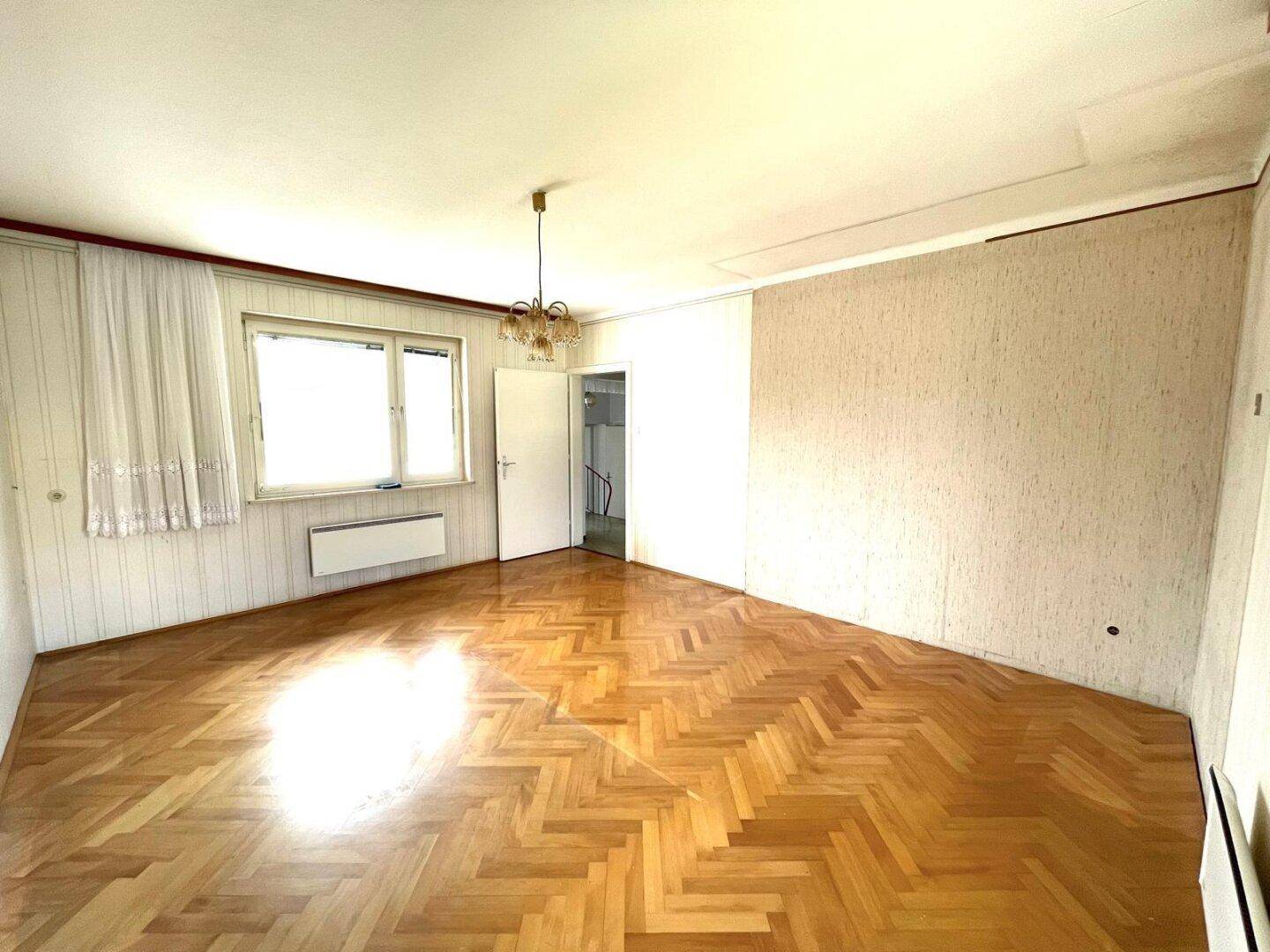 Geräumiges Zimmer mit Parkettboden und viel Tageslicht.