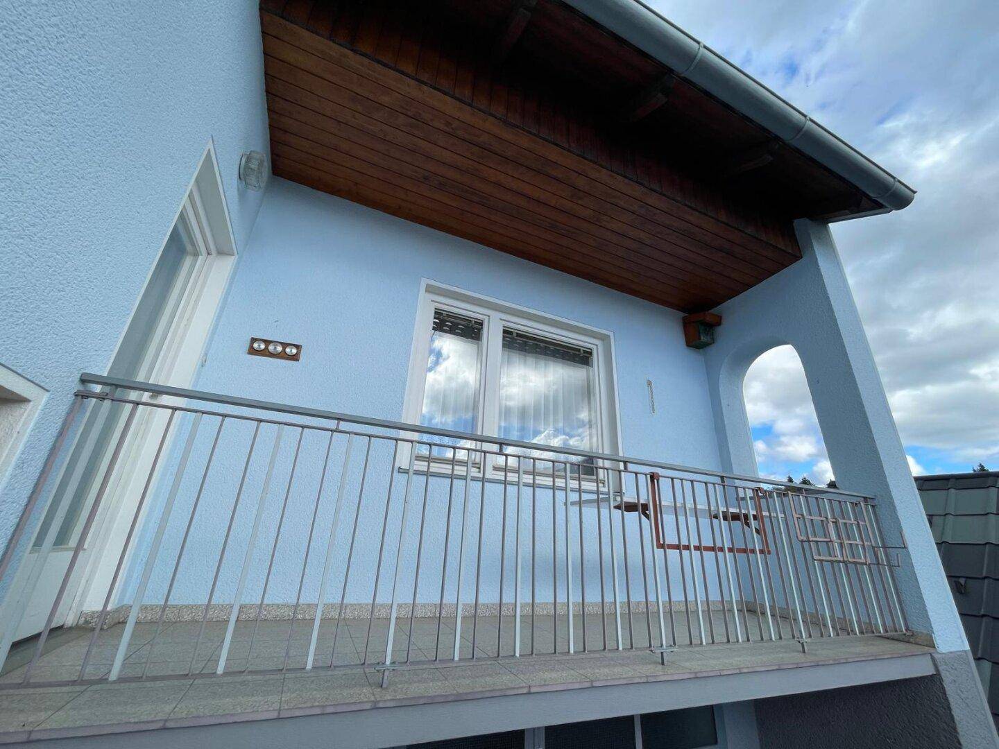 Balkon mit Metallgeländer und Holzdach, bietet Blick auf die Umgebung.