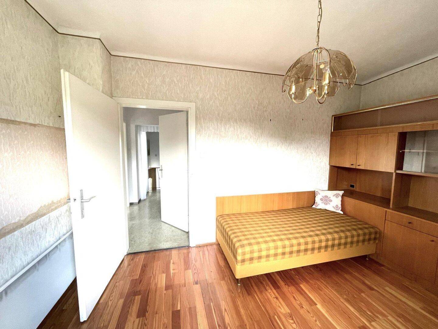 Schlafzimmer mit Parkettboden, Bett und Einbauschrank.