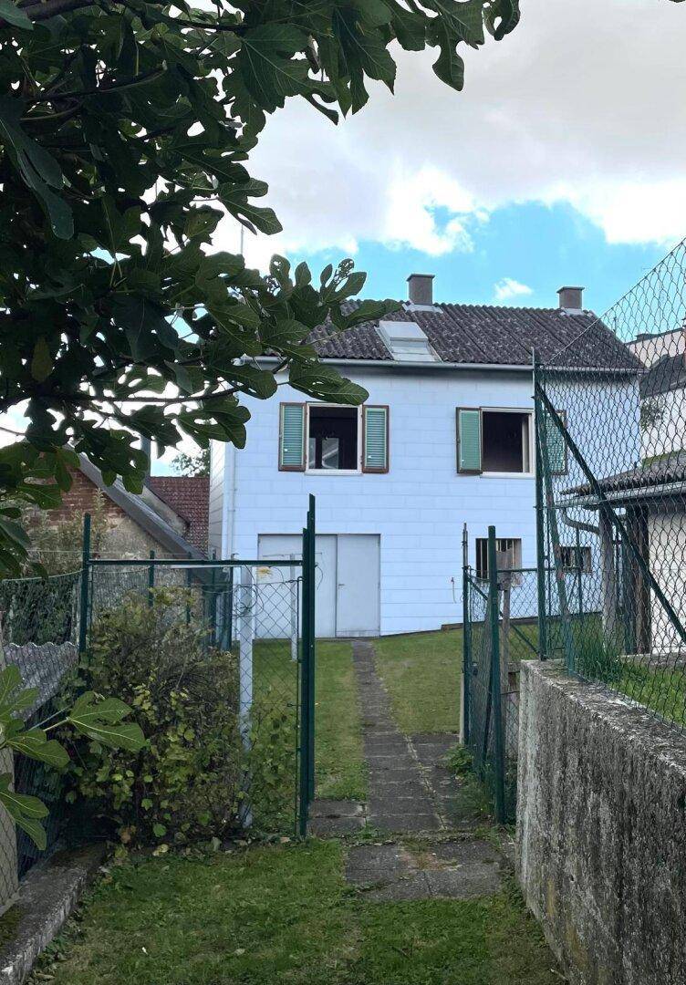 Hinterer Garten mit Zugang zum Haus und grüner Umgebung.