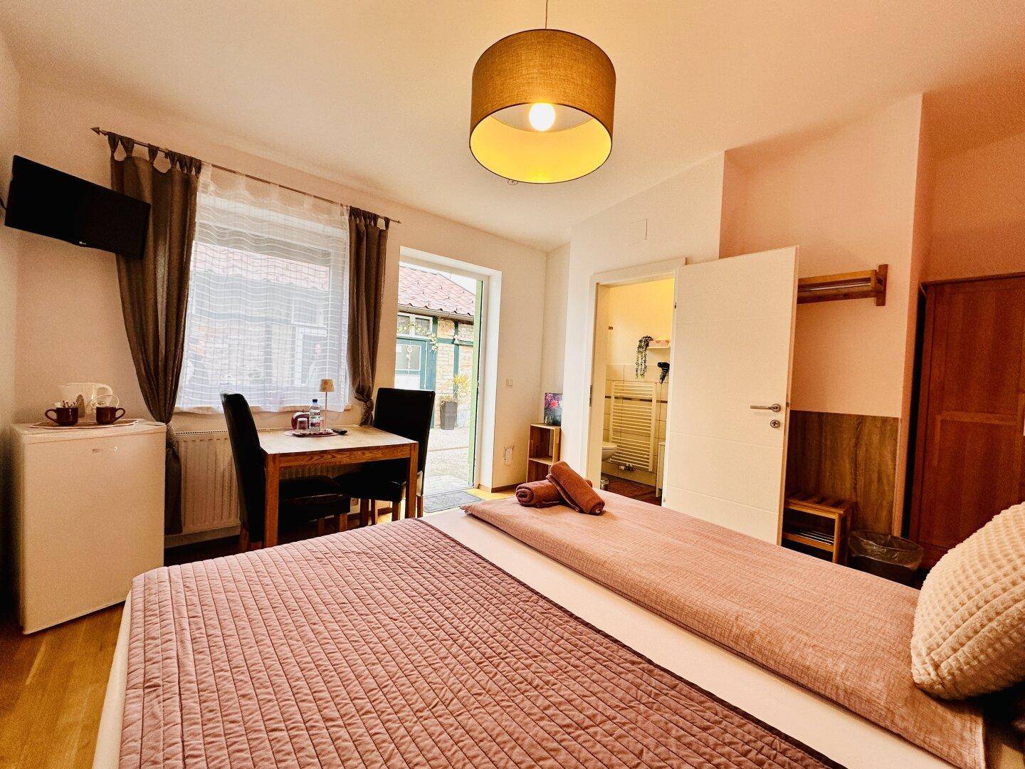 Gemütliches Schlafzimmer mit Essbereich, Minikühlschrank und direktem Zugang zum Außenbereich.