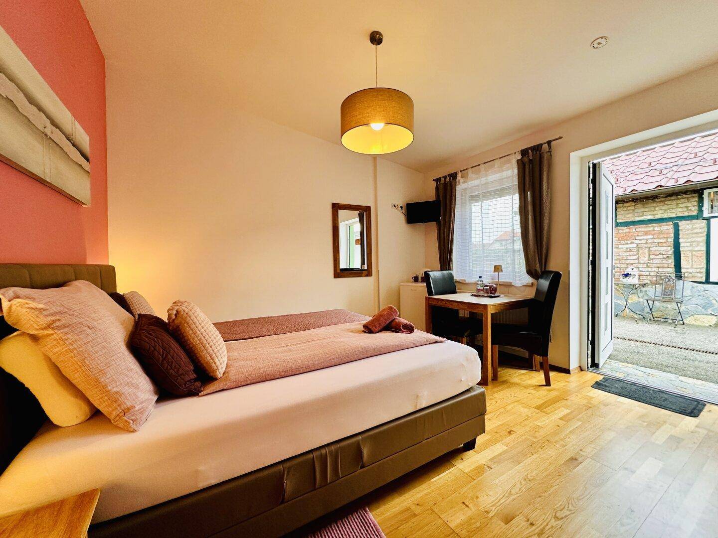 Schlafzimmer mit Doppelbett und direktem Zugang zu einer kleinen Terrasse im Freien.