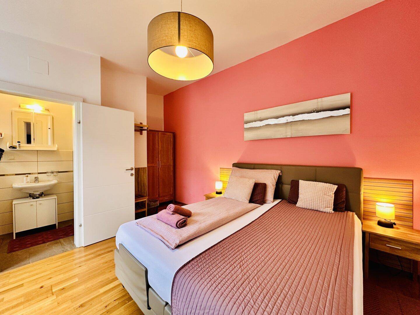 Helles Schlafzimmer mit Doppelbett, Nachttischen und Zugang zu einem privaten Badezimmer.
