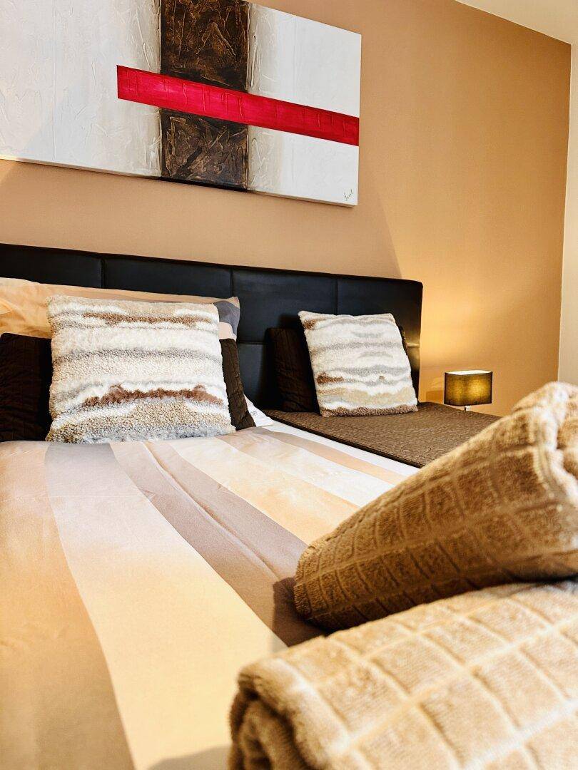 Detailansicht des Bettes in einem Schlafzimmer mit Kissen und gerollten Handtüchern.