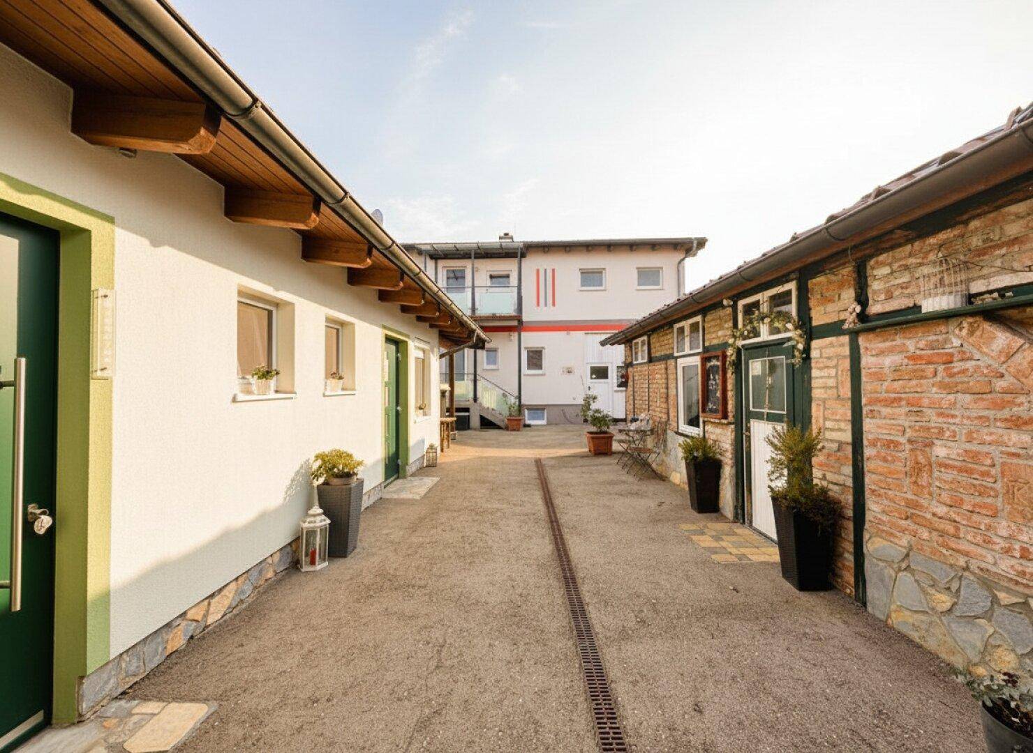 Blick auf einen gepflasterten Innenhof zwischen zwei Gebäuden mit unterschiedlichen Fassaden.
