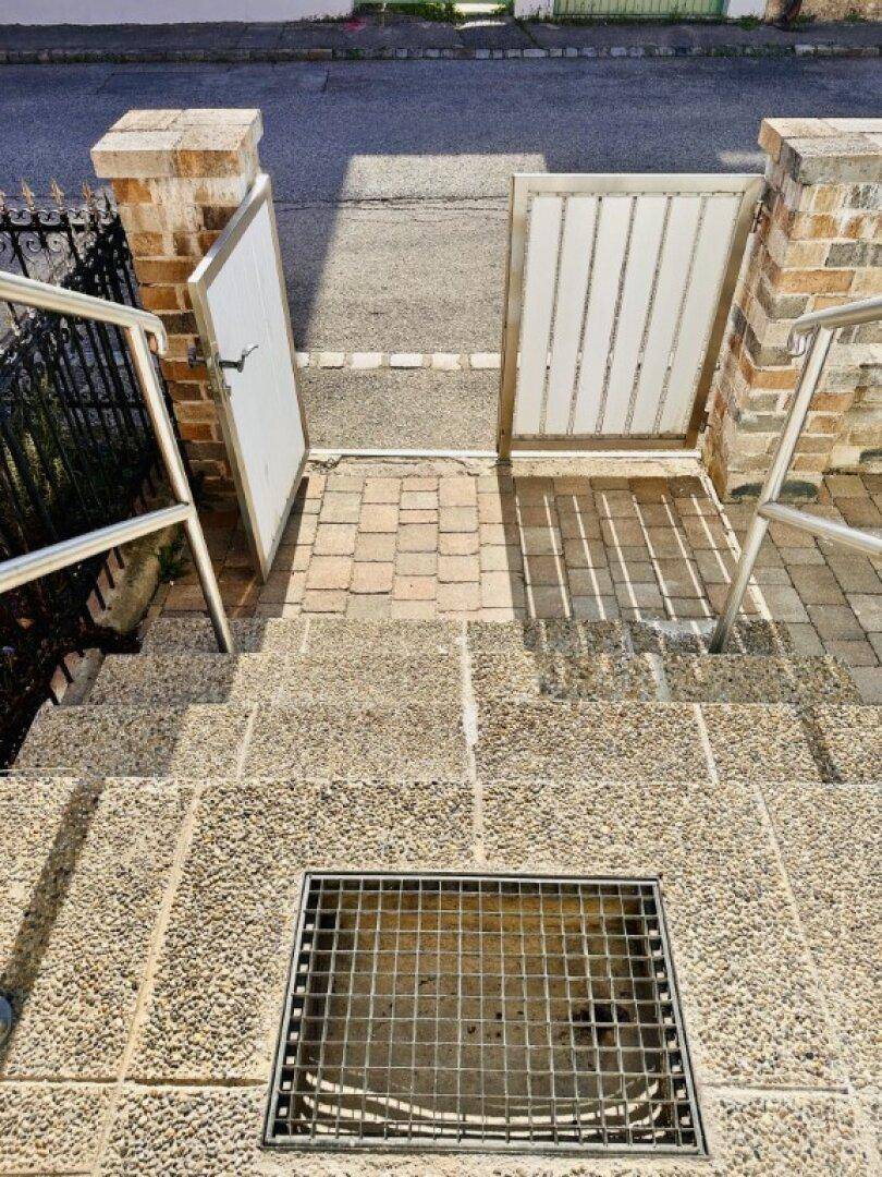 Steintreppe zum Eingangsbereich mit Metallgeländer und einem Gitterrost.