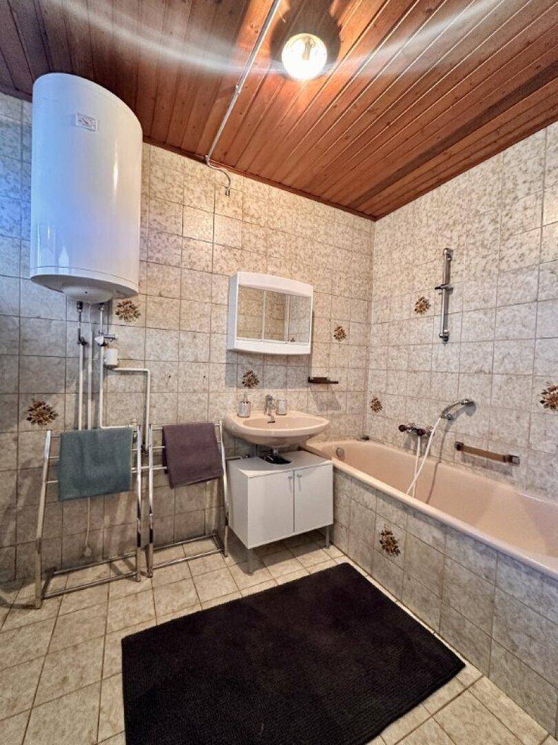 Badezimmer mit Badewanne, Waschbecken und Fliesen im 80er-Jahre-Stil.