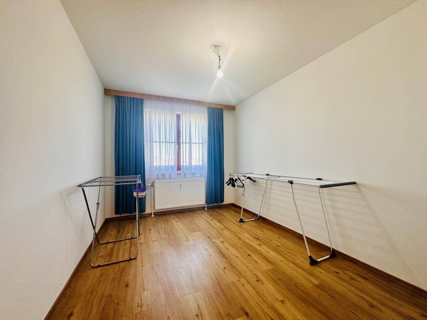 Geräumiger Raum mit Holzboden und Fenster, derzeit als Hauswirtschaftsraum genutzt.