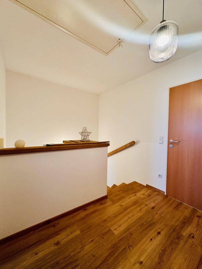 Heller Flur im Obergeschoss mit Holzboden und Zugang zu weiteren Räumen.