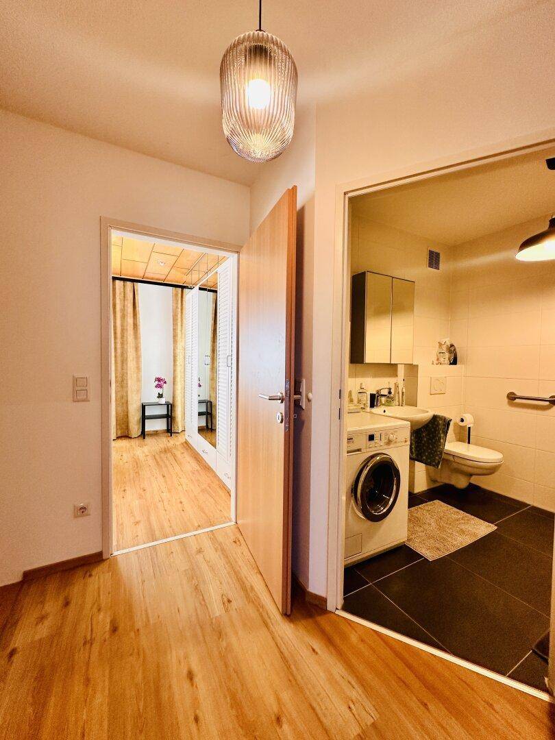 Heller Flur mit Holzboden, der zu einem Schlafzimmer und einem Badezimmer führt.