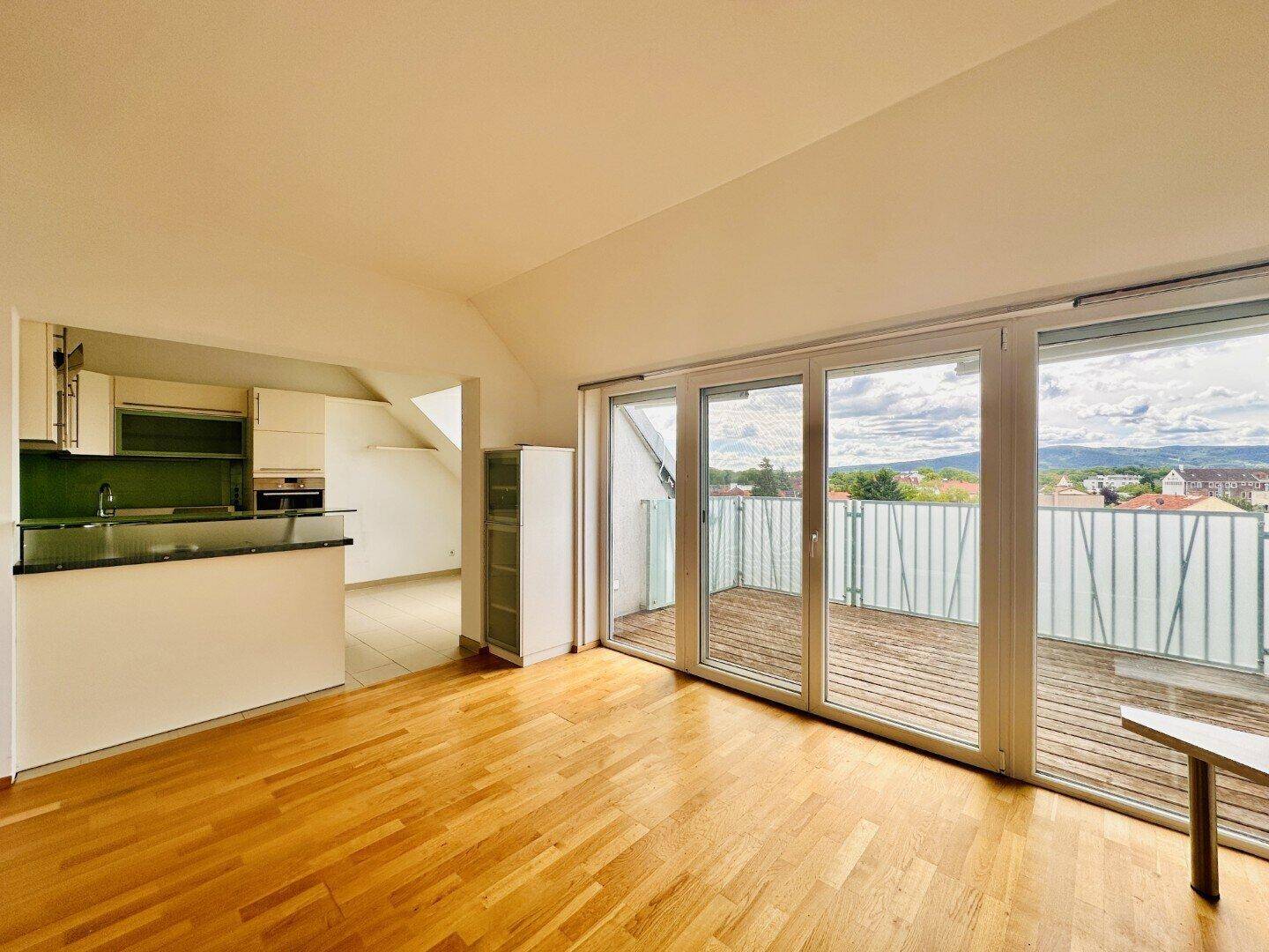 Offener Wohnbereich mit Holzboden, Zugang zur Terrasse und Blick auf die Umgebung.