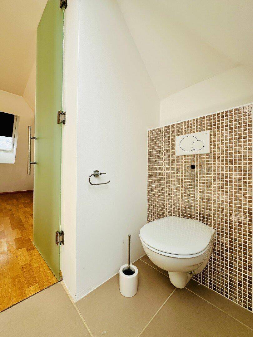 Modernes WC mit Wand-WC, Mosaikfliesen und Milchglastür.