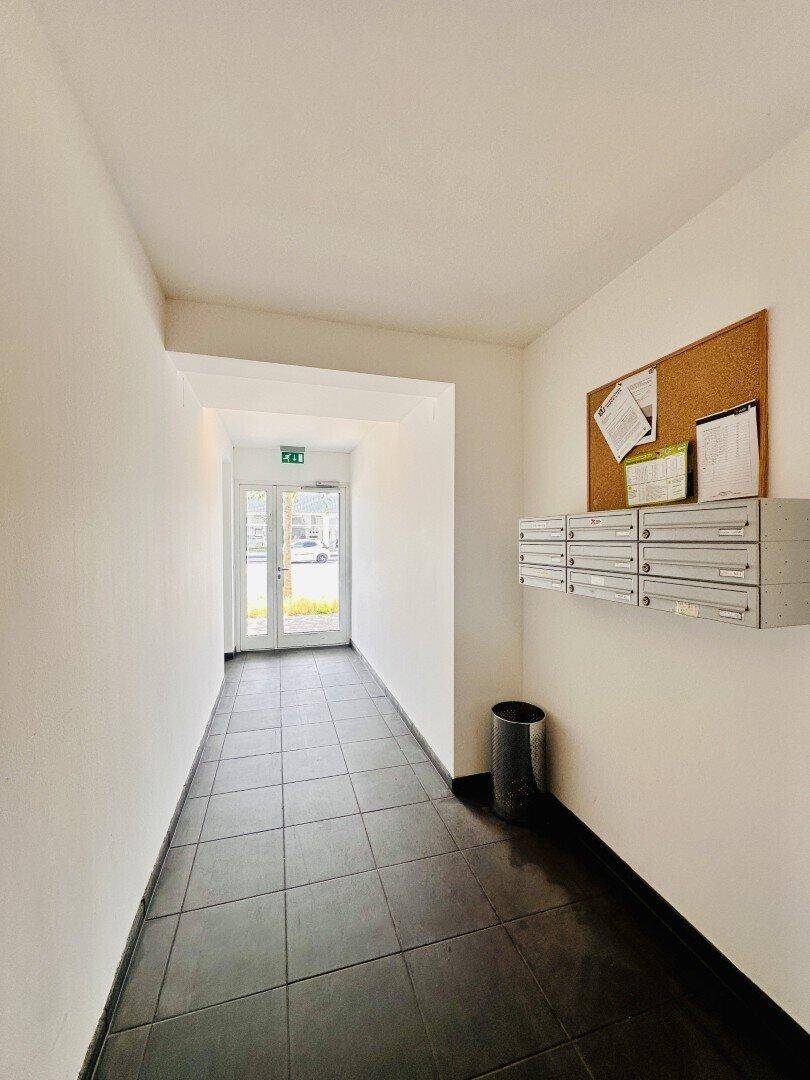 Heller Eingangsbereich mit Fliesenboden, Briefkästen und Zugang nach draußen.