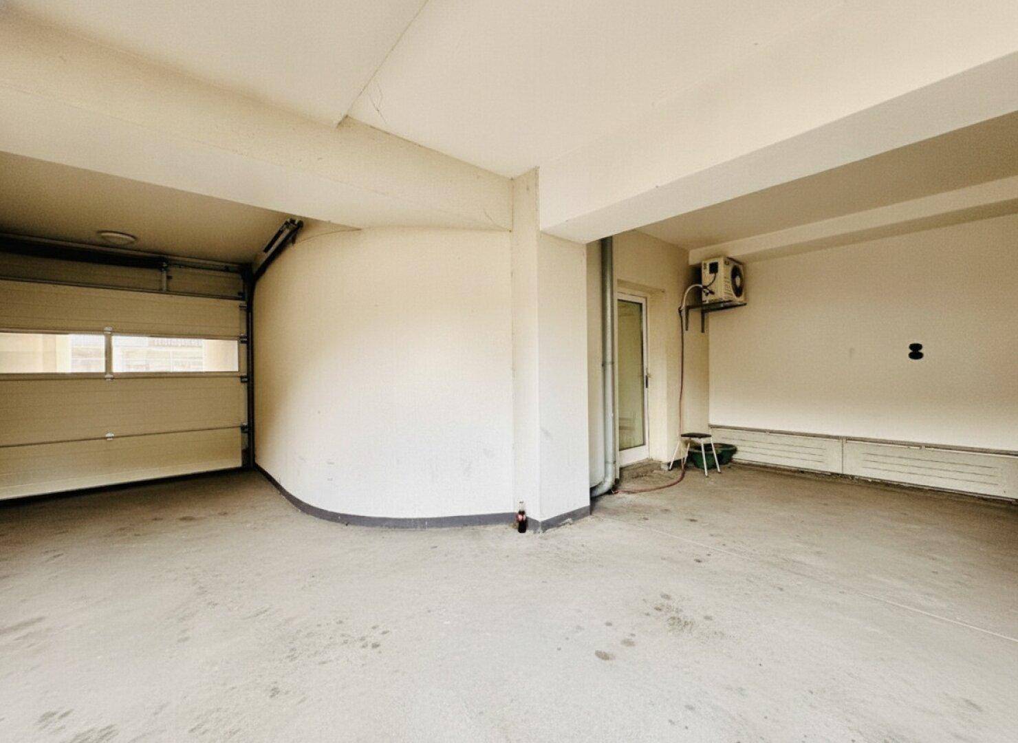 Geräumige Tiefgarage mit Rolltor und Betonboden.