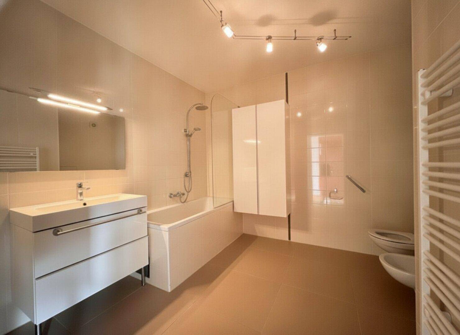 Modernes Badezimmer mit Badewanne, Waschtisch, Bidet und beheiztem Handtuchhalter.