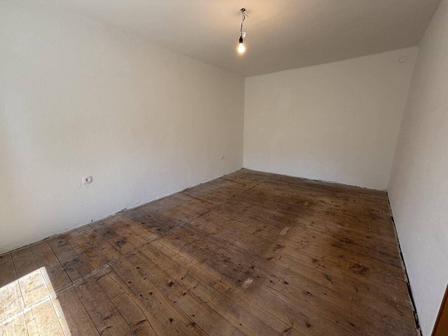 Geräumiges Zimmer mit freigelegten Dielenböden, bereit für eine individuelle Gestaltung.