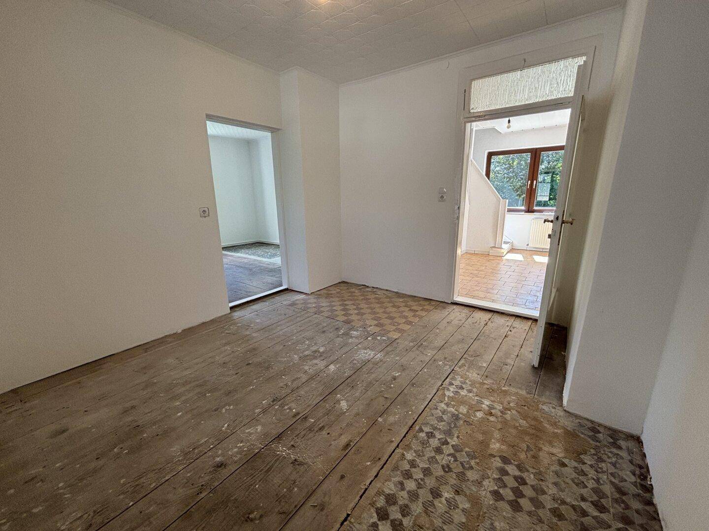 Geräumiges Zimmer mit freigelegten Dielenböden und offenen Zugängen zu anderen Bereichen.