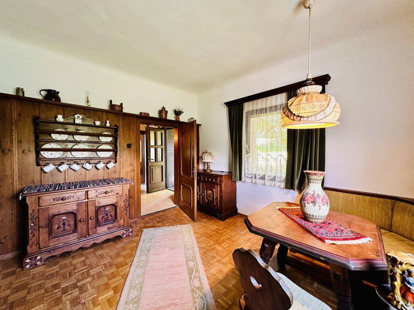 Rustikaler Essbereich mit Holzboden, traditionellen Möbeln und Blick ins Grüne.