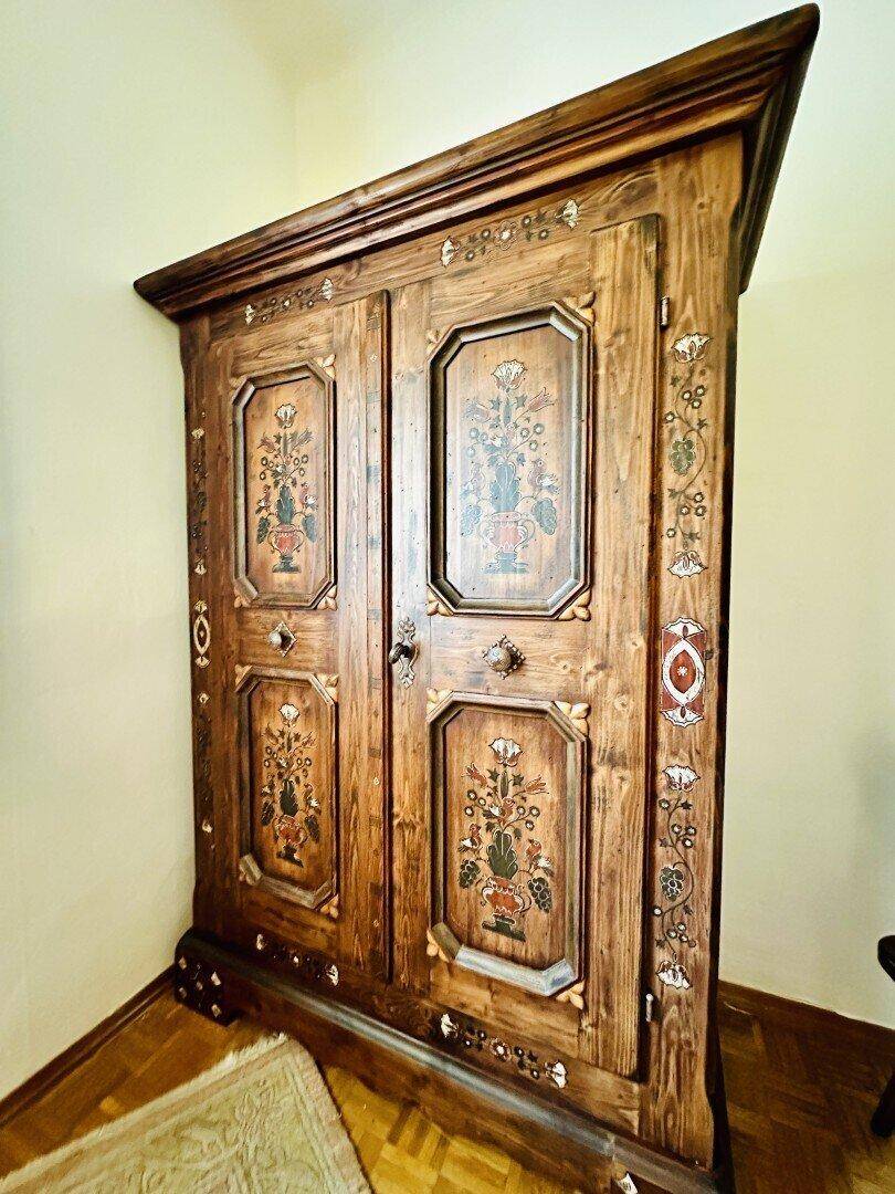 Antiker Holzschrank mit aufwendigen Schnitzereien und floralen Verzierungen.