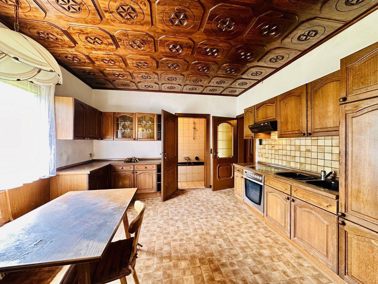 Geräumige Küche mit Holzschränken, Essbereich und traditioneller Deckenverkleidung.