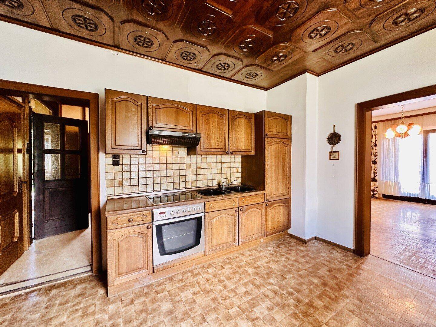 Funktionale Küche mit Holzschränken, Fliesenboden und traditionellem Design.