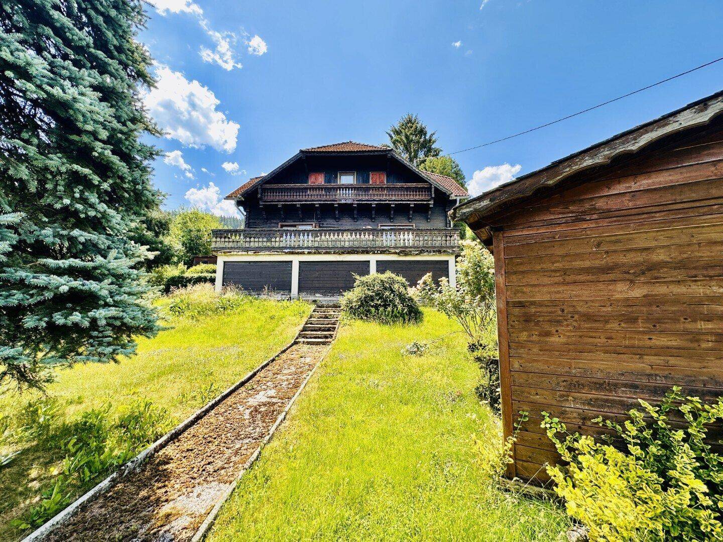 Traditionelles Holzhaus mit Garten und Gartenweg, umgeben von Natur.