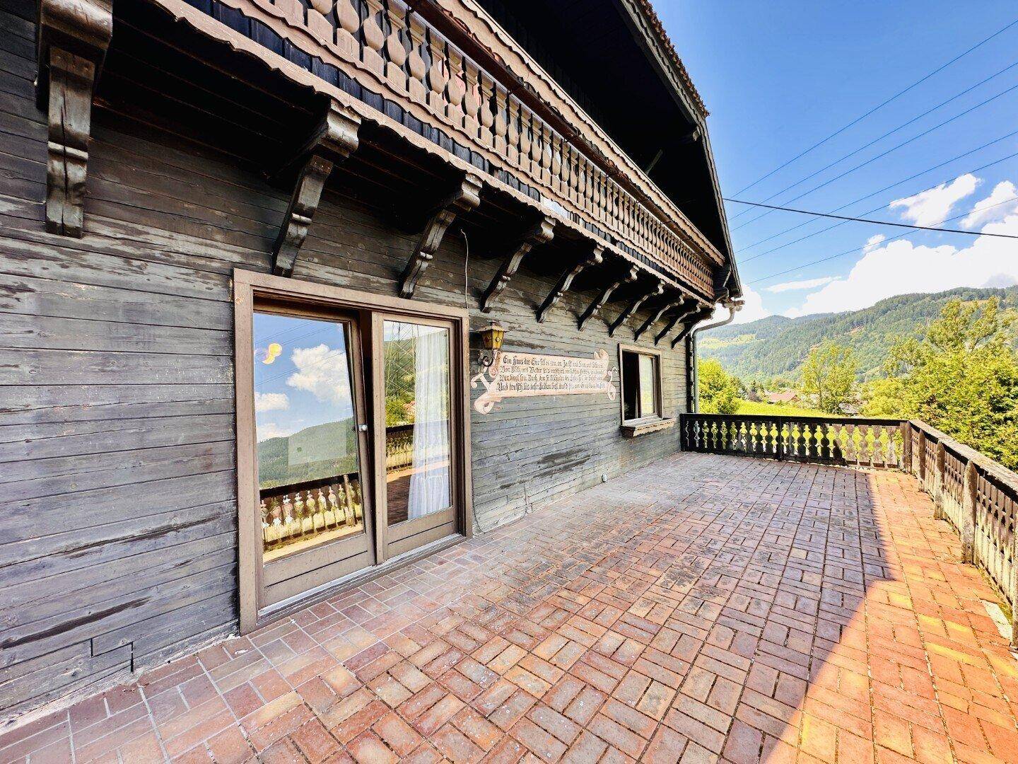 Große gepflasterte Terrasse mit traditionellem Holzgeländer und Bergblick.