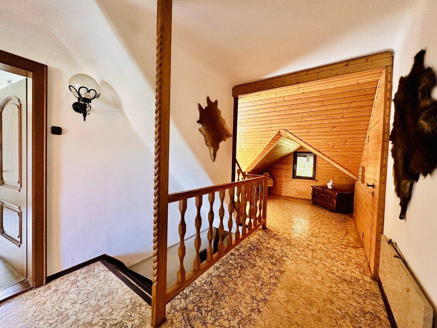 Heller Flur im Obergeschoss mit Holzgeländer und Blick in den Dachbereich.