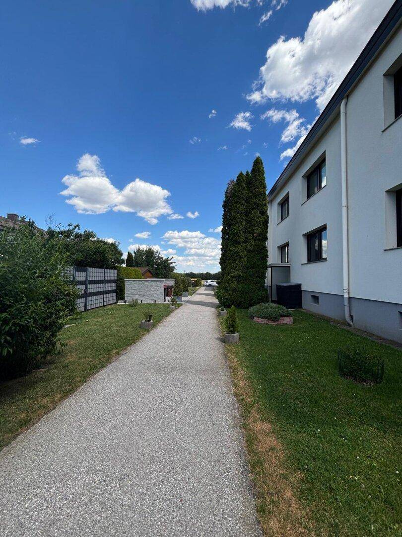 Außenansicht des Gebäudes mit einem Gehweg und gepflegter Grünfläche.