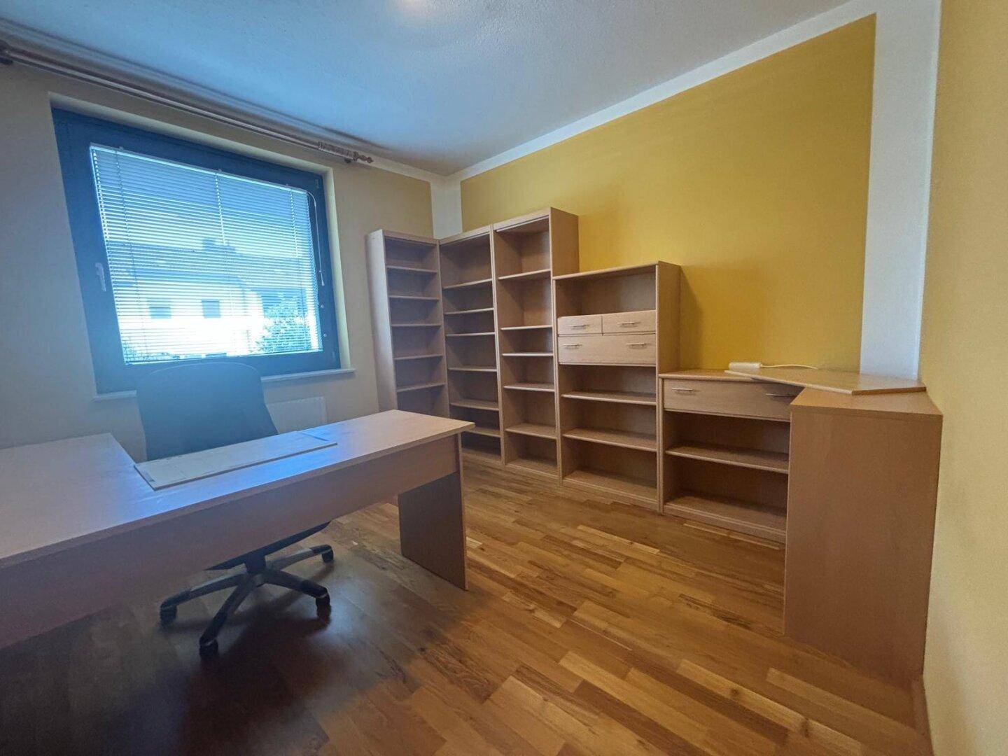 Geräumiges Arbeitszimmer mit gelben Wänden, Holzboden und Bücherregalen.