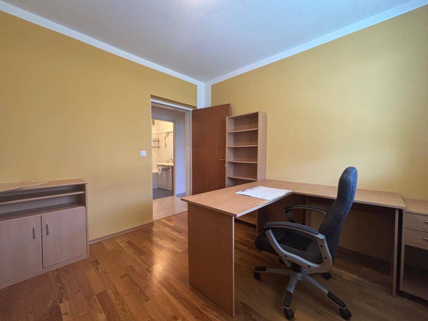 Arbeitszimmer mit gelben Wänden, Holzboden und Schreibtisch.
