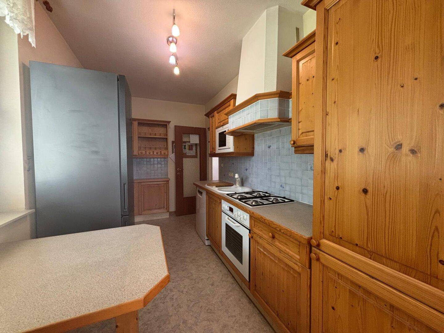 Traditionelle Holzküche mit Gasherd, Backofen und großem Kühlschrank.