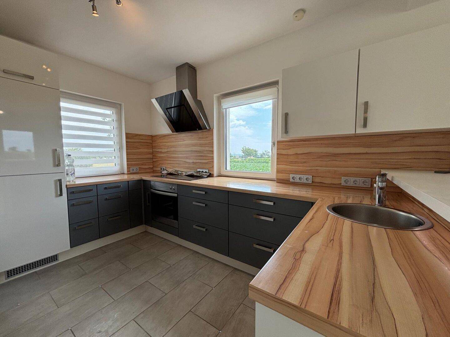 Saubere und moderne Küche mit Holzdetails und grauen Schränken, ideal für kulinarische Aktivitäten.