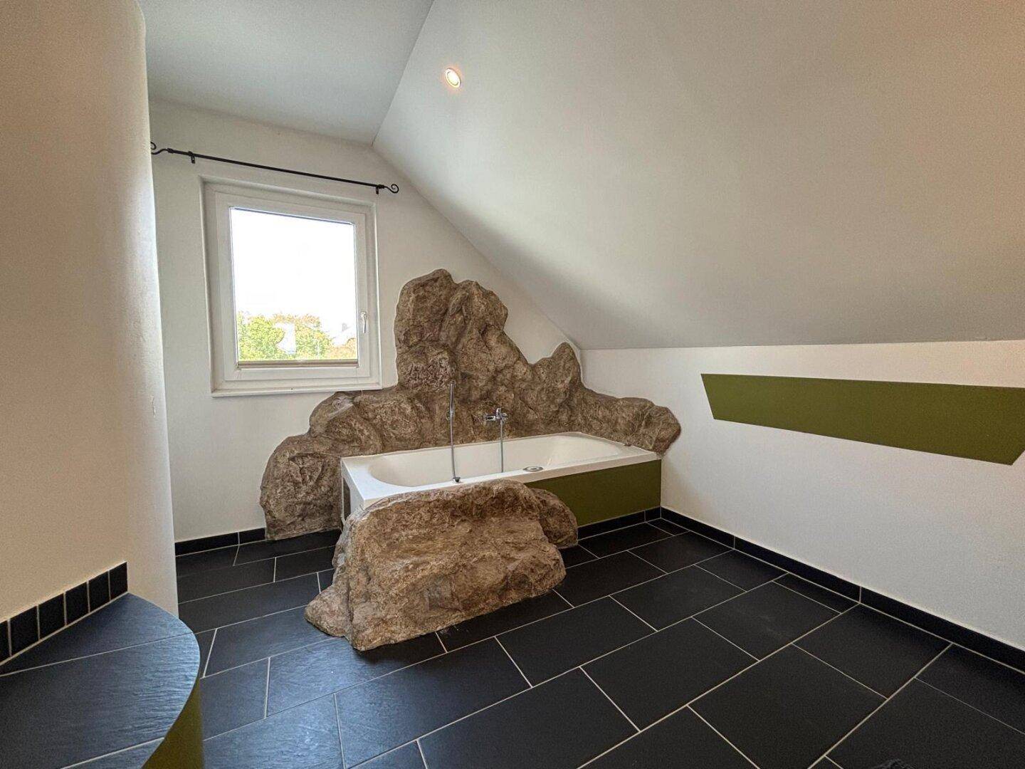 Modernes Badezimmer mit Whirlpool, Fenster und dunklen Fliesen.