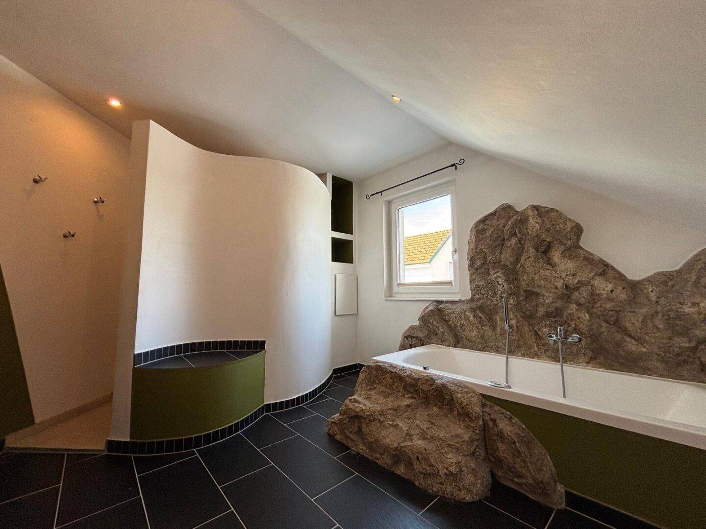 Helles Badezimmer mit Whirlpool, Dusche und Fenster im Dachgeschoss.