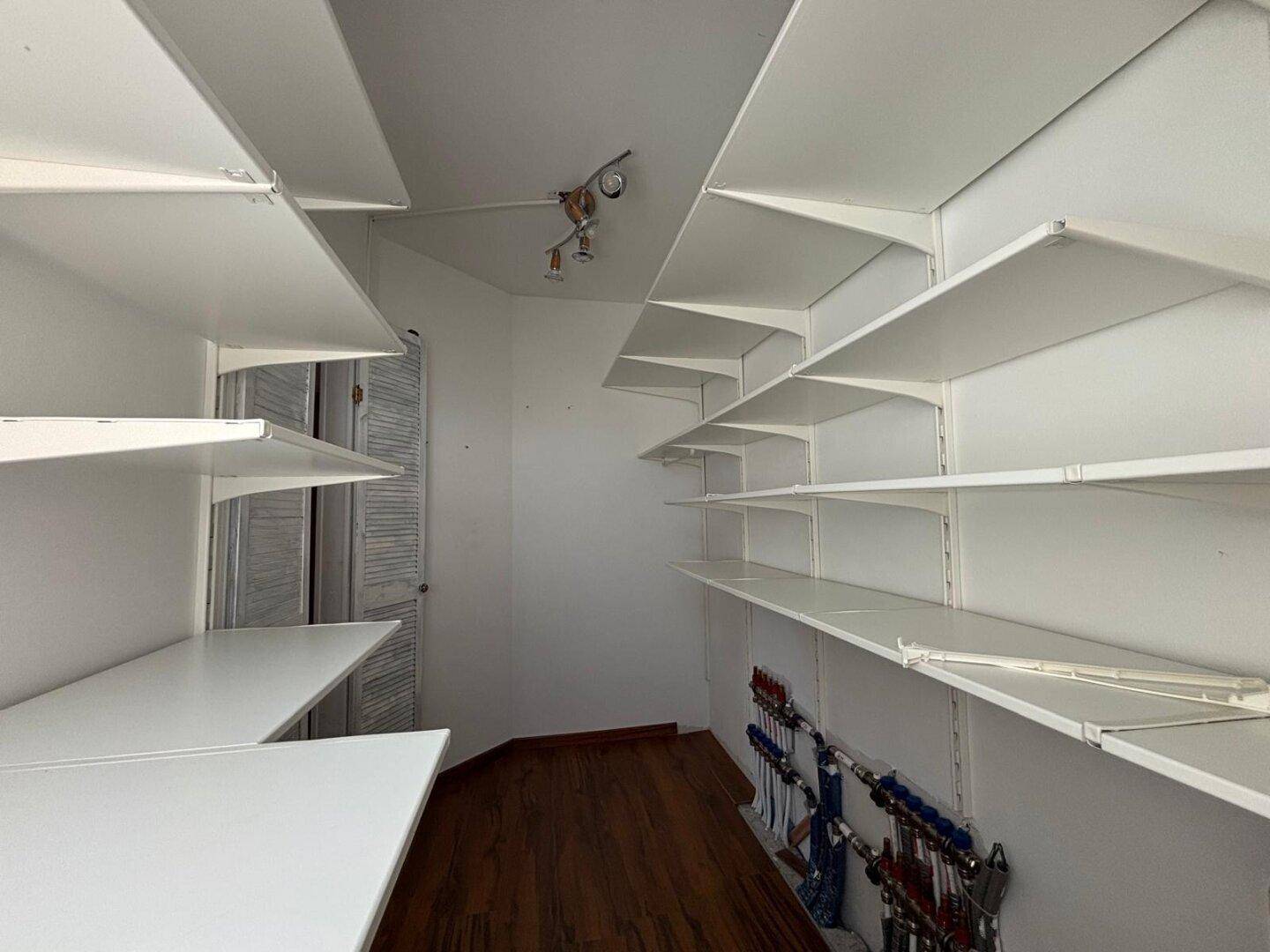 Praktischer begehbarer Kleiderschrank mit vielen Regalen und Holzboden.