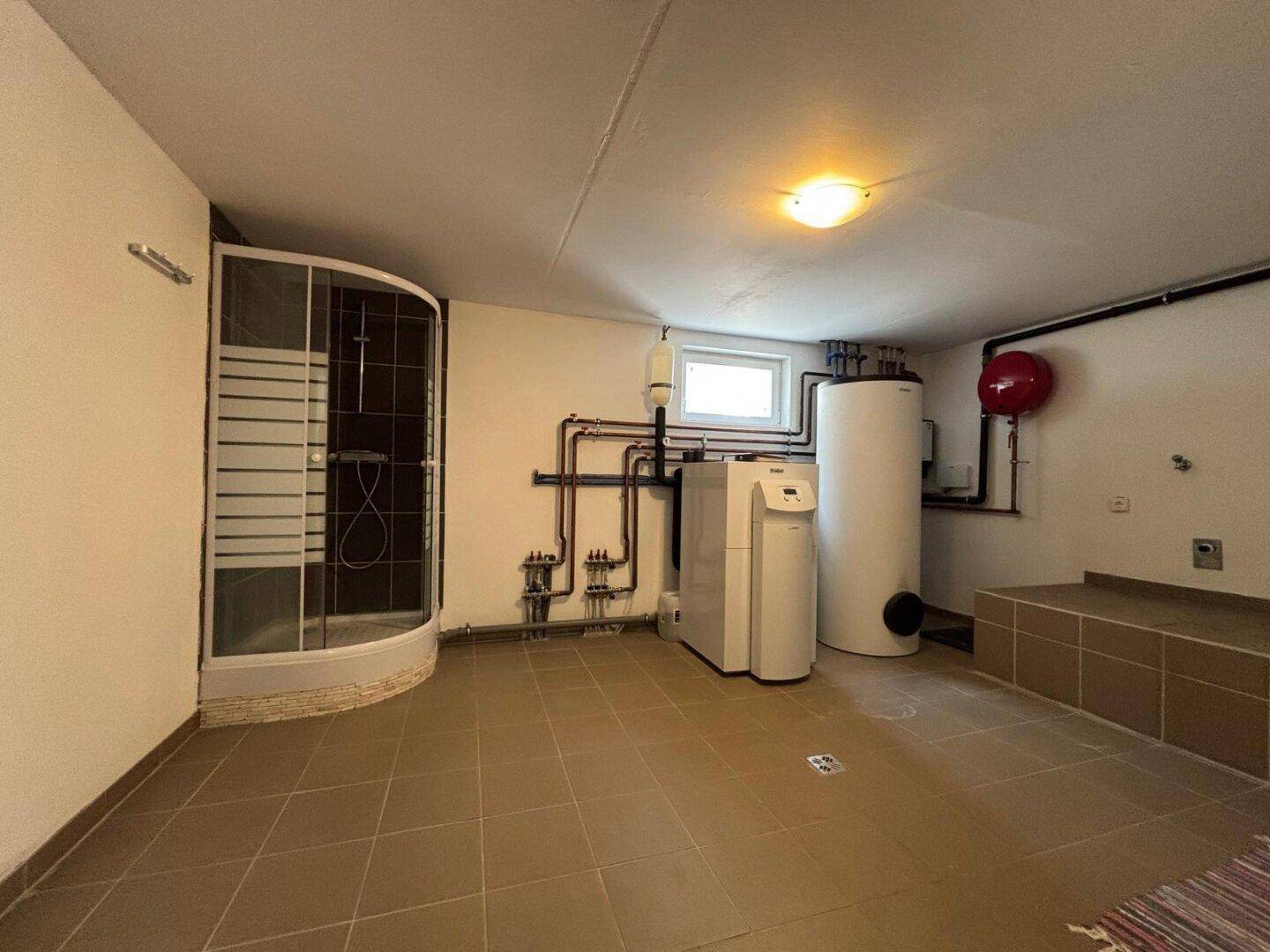 Hauswirtschaftsraum mit Duschkabine und Heizungsinstallationen, praktisch und funktional gestaltet.