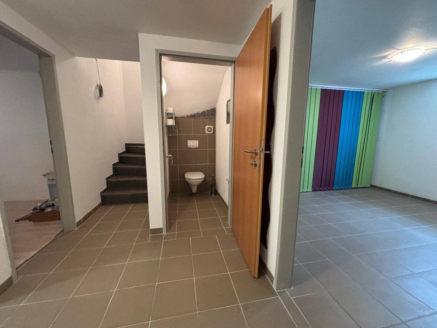 Heller Eingangsbereich mit Fliesenboden, Treppe und Zugang zu einem Gäste-WC.