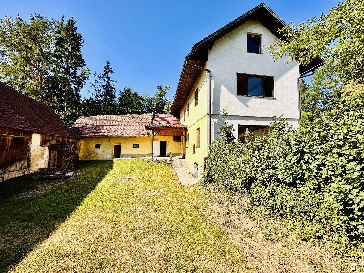 Ländliches Anwesen mit Haupthaus und Nebengebäuden, umgeben von viel Grün.
