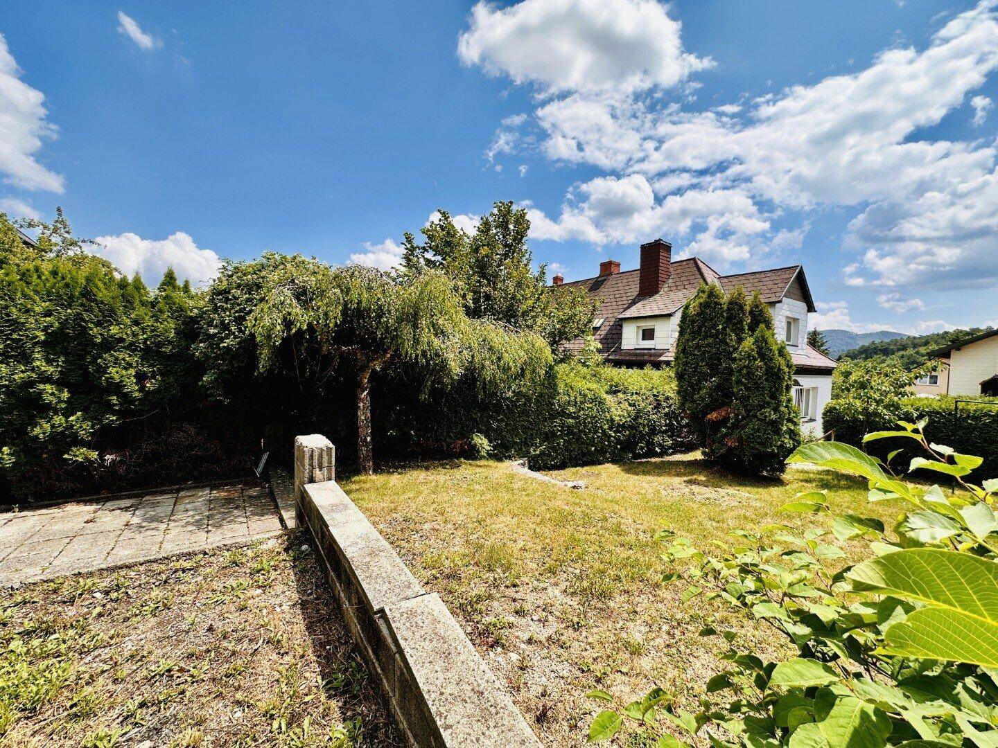 Weitläufiger Garten mit Rasen, Bäumen und Blick auf die umliegende Landschaft.