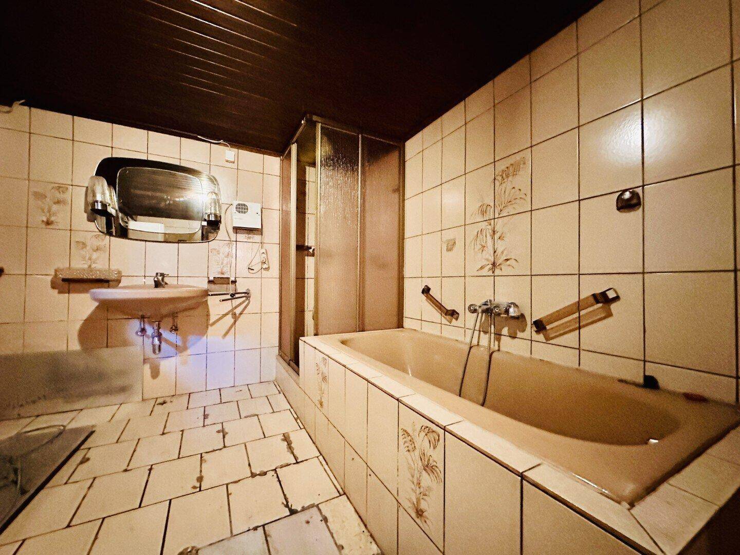 Badezimmer mit beigefarbenen Fliesen, Badewanne, Waschbecken und Duschkabine.