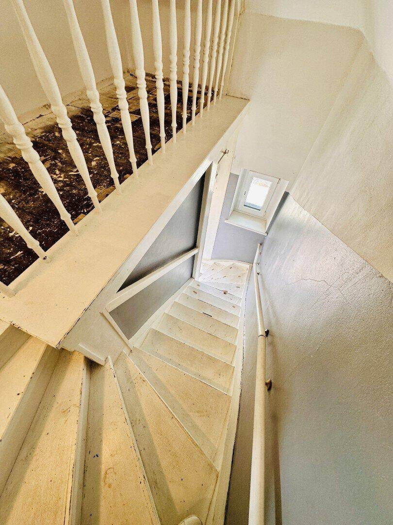 Holztreppe mit weißem Geländer, die in das untere Stockwerk führt.