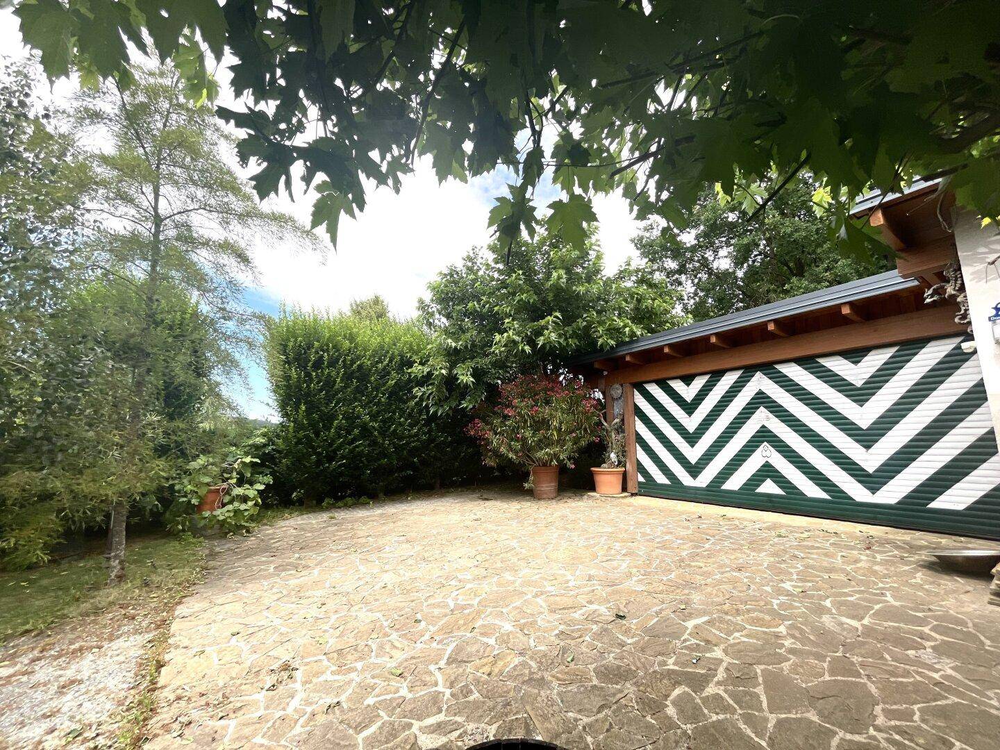 Geräumiger Parkbereich mit Natursteinpflaster vor einer Garage mit auffälligem Zickzack-Muster.