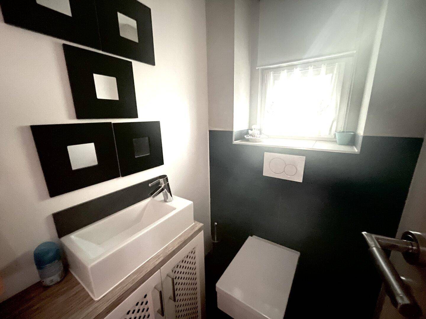 Modernes Gäste-WC mit Fenster, wandhängendem WC und kleinem Waschbecken.
