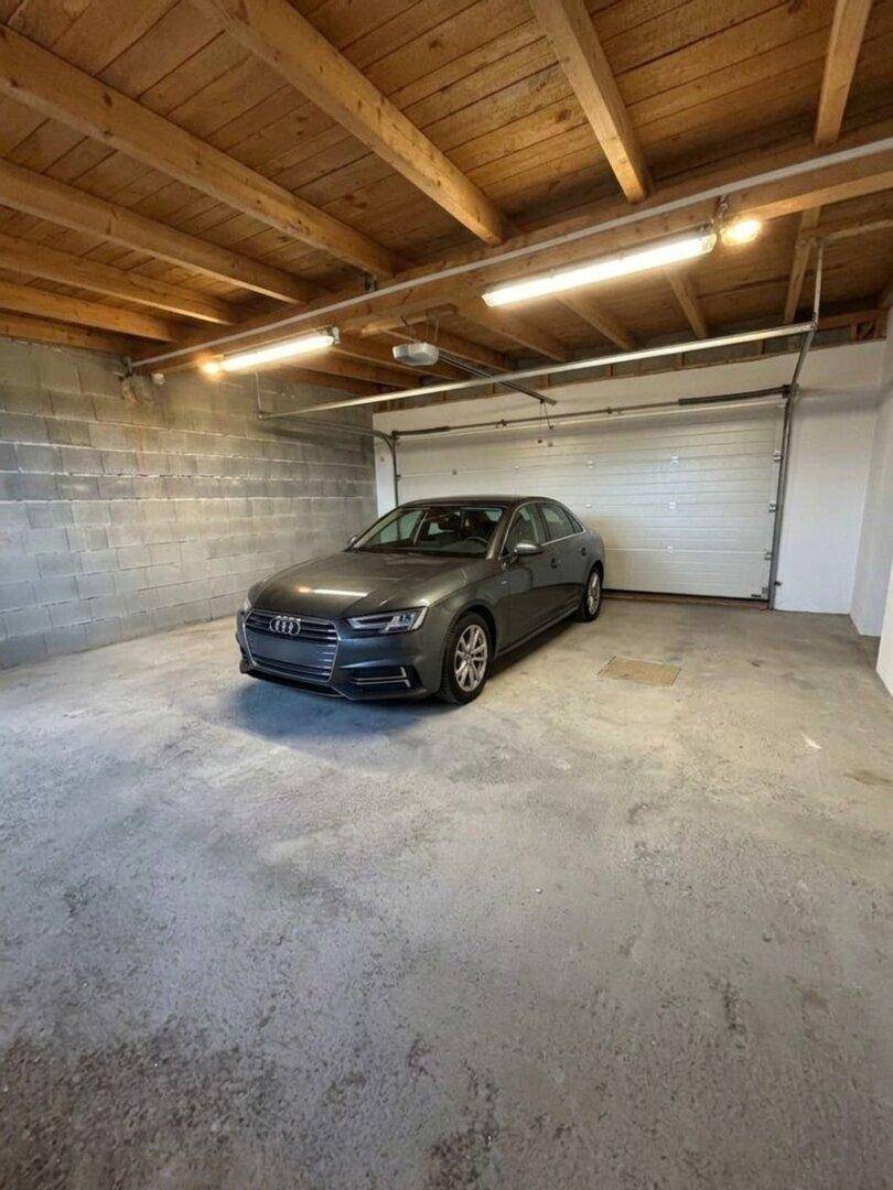 Geräumige Garage mit Betonboden und Holzbalkendecke, bietet Platz für ein Fahrzeug.